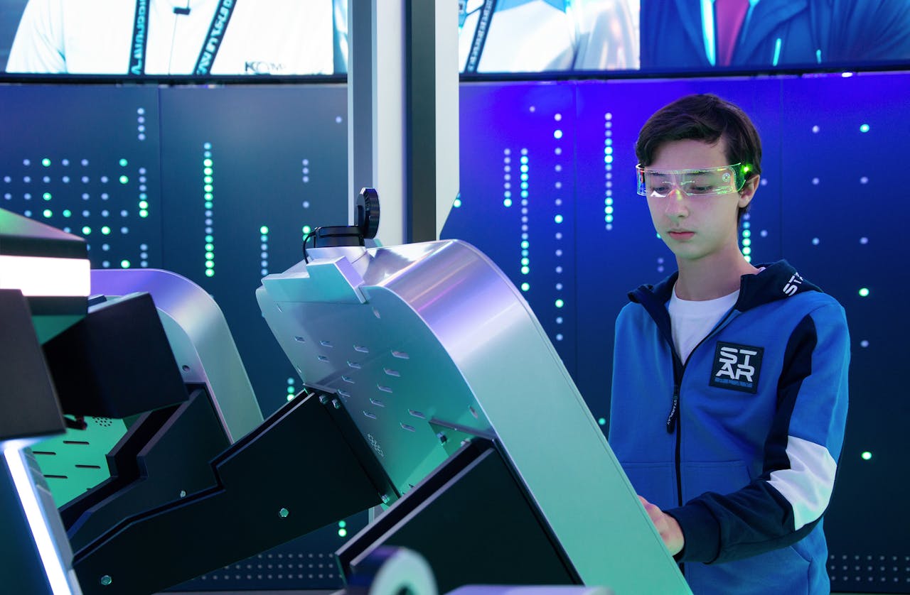 Teenager interacts with futuristic device using VR goggles in tech environment.